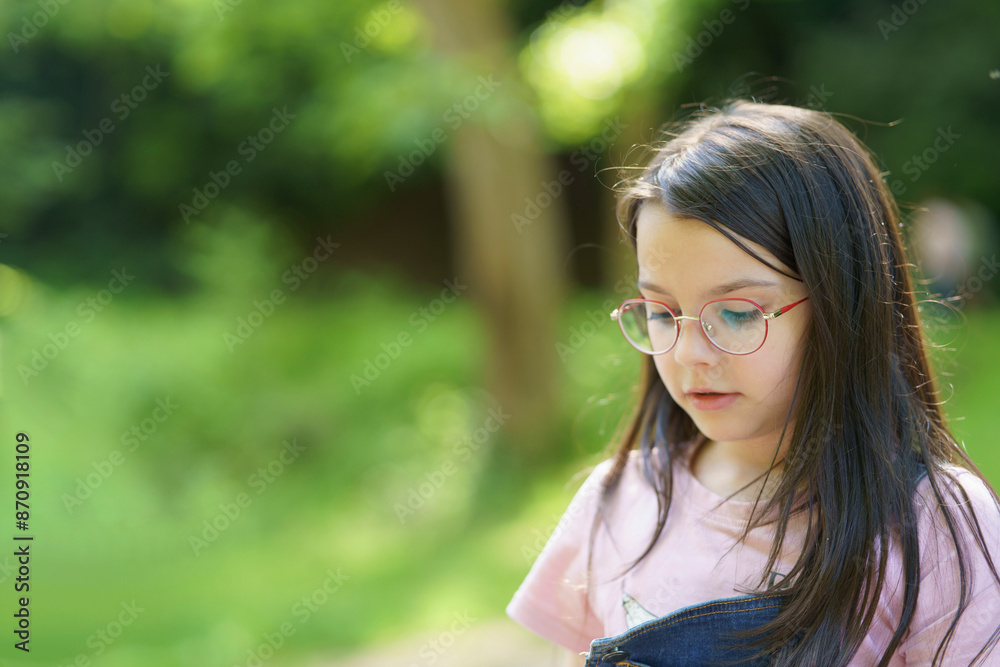 Little cute teenage girl wearing glasses on a blurred summer natural background. Happy childhood concept Little cute teenage girl wearing glasses on a blurred summer natural background. Happy childhood concept