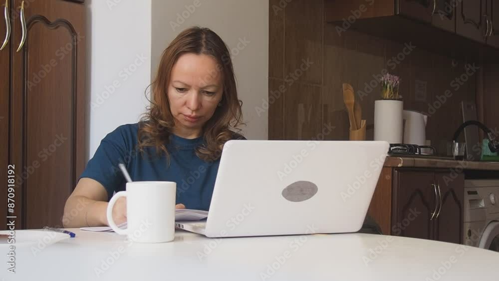 Busy woman eating, drinking coffee, talking on the phone, working on laptop at the same time. Freelancer works at home. woman in the kitchen studying online, talking on video, video call Busy woman eating, drinking coffee, talking on the phone, working on laptop at the same time. Freelancer works at home. woman in the kitchen studying online, talking on video, video call