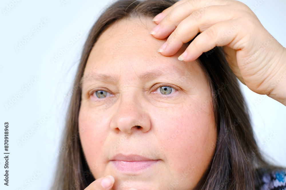 close-up of charismatic mature woman 50 years old looks carefully examines wrinkles on face, skin folds, age-related skin changes, aesthetic injection cosmetology, care anti-aging procedures close-up of charismatic mature woman 50 years old looks carefully examines wrinkles on face, skin folds, age-related skin changes, aesthetic injection cosmetology, care anti-aging procedures