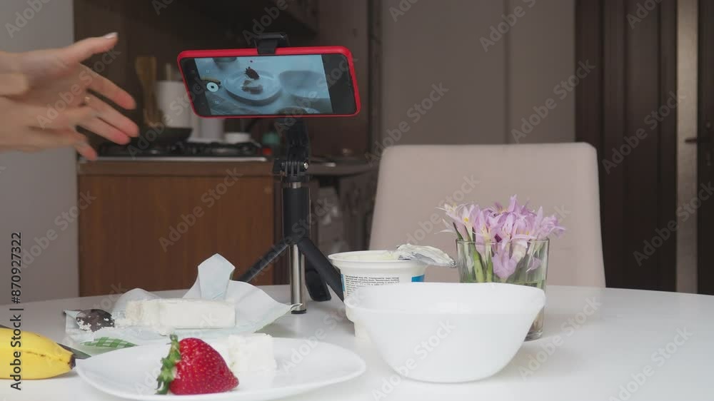 girl blogger films breakfast for video blog, content for social networks, stories. Hands with the phone close-up pictures of food. Breakfast for two : yogurt, coffee, fruit , toast., strawberry, banan