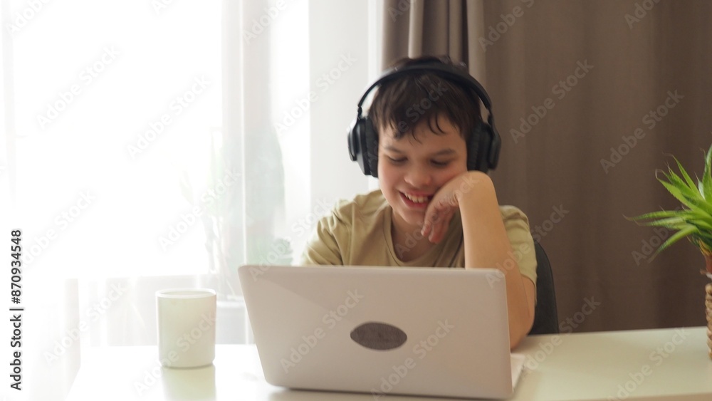 boy, teenager, schoolboy, wearing headphones, uses a laptop and communicates on the Internet at home. homeschooling, distance learning, online e. Watches videos, communicates on social networks, makes boy, teenager, schoolboy, wearing headphones, uses a laptop and communicates on the Internet at home. homeschooling, distance learning, online e. Watches videos, communicates on social networks, makes