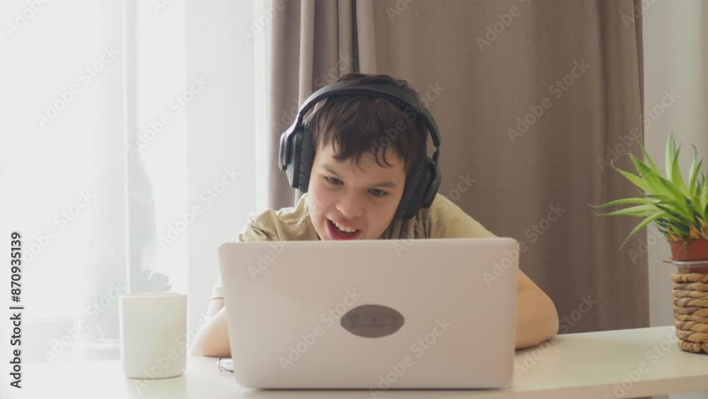 boy, teenager, schoolboy, wearing headphones, uses a laptop and communicates on the Internet at home. homeschooling, distance learning, online e. Watches videos, communicates on social networks, makes boy, teenager, schoolboy, wearing headphones, uses a laptop and communicates on the Internet at home. homeschooling, distance learning, online e. Watches videos, communicates on social networks, makes