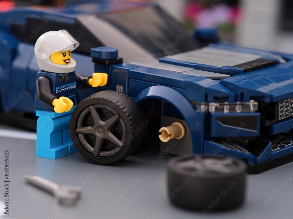 Fototapeta premium Tambov, Russian Federation - July 01, 2024 Lego driver minifigure changing a wheel of Lego Ford Mustang Dark Horse sports car.
