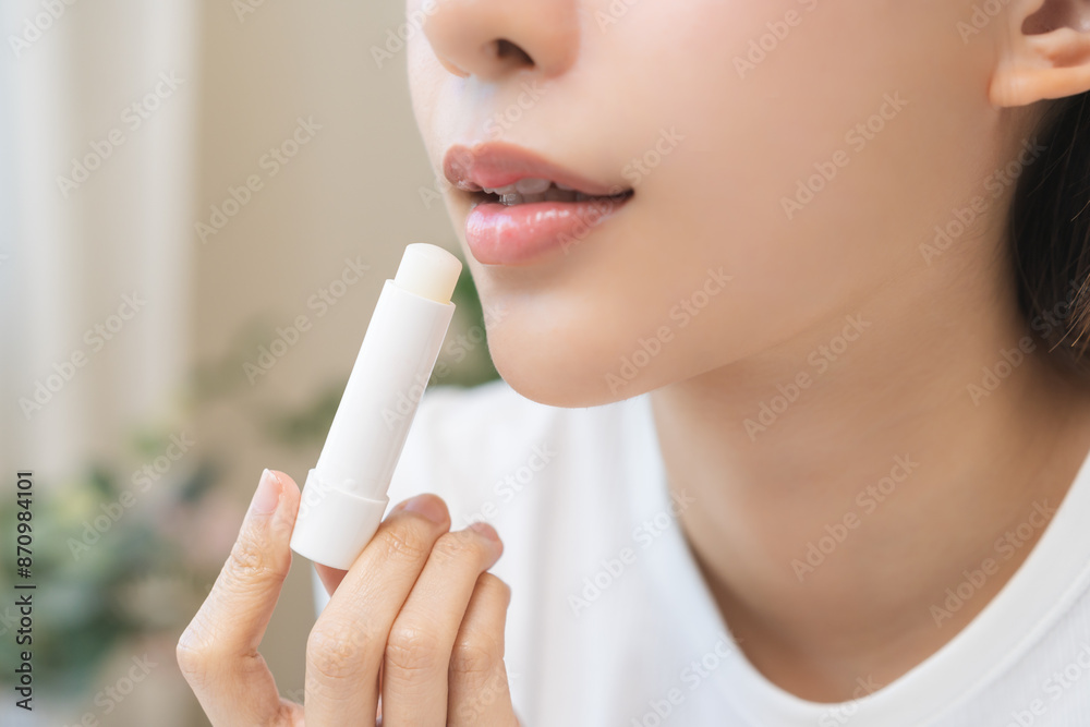 Lip care protection concept, pretty asian young woman, girl hand applying lipstick balm with moisturising on dry mouth from natural beauty product, skincare routine, makeup and cosmetics on background Lip care protection concept, pretty asian young woman, girl hand applying lipstick balm with moisturising on dry mouth from natural beauty product, skincare routine, makeup and cosmetics on background