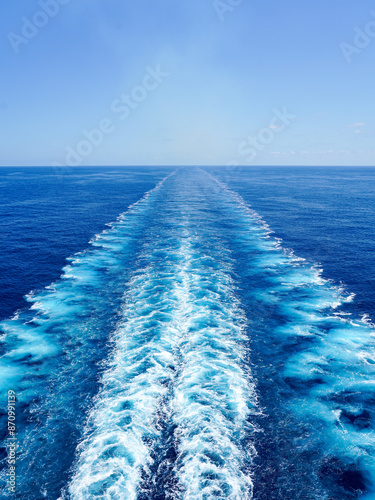 Fotografija Wide turbulent white foam water trail behind a large cruise ship in a calm blue