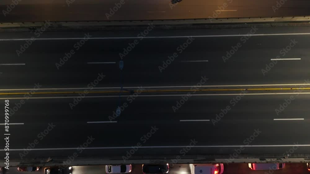 Aerial top view of many cars and trucks driving on asphalt multi level expressway at night illuminated by street lights Aerial top view of many cars and trucks driving on asphalt multi level expressway at night illuminated by street lights