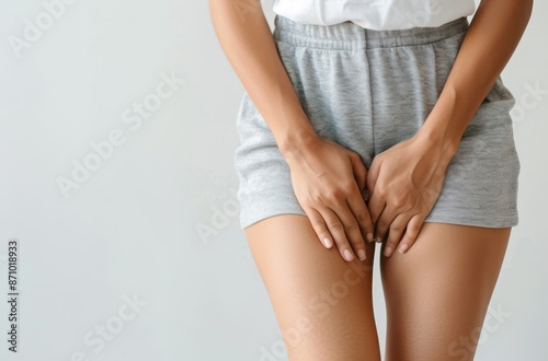A woman is wearing grey shorts and holding her crotch by AI generated image