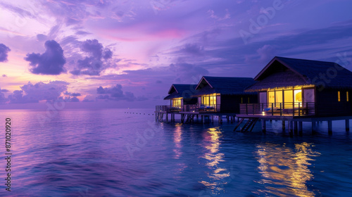 Sunset casts violet hues over the sea surrounding the Maldives bungalows.