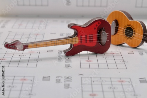  toy guitars miniatures on a music sheet with notes and chords