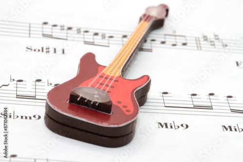 a toy guitar miniature on a music sheet with notes and chords