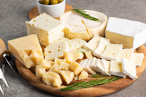 Wooden board with various cheese and olives. Brie. Camembert. Parmesan, feta, blue cheese. Italian, French cheese.