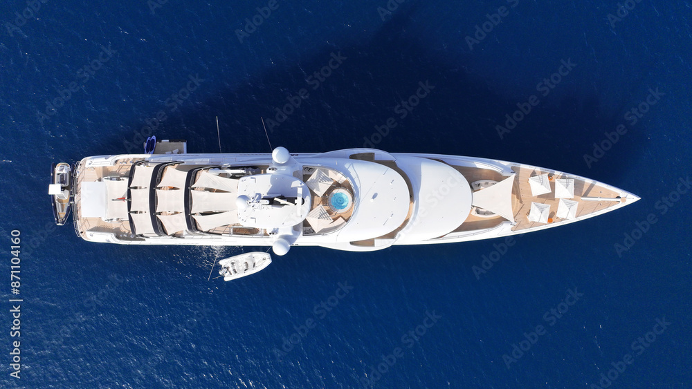 Aerial drone top down photo of luxury yacht with wooden deck anchored in deep blue Aegean sea, Mykonos island, Cyclades, Greece