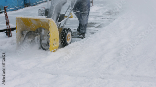 Janitor cleans snow with tractor. Snow removal. Cleaning the streets from snow. Snowblower. © DenisProduction.com