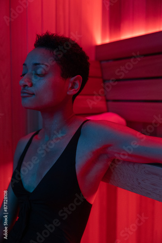 Woman unwinding in red illuminated sauna
