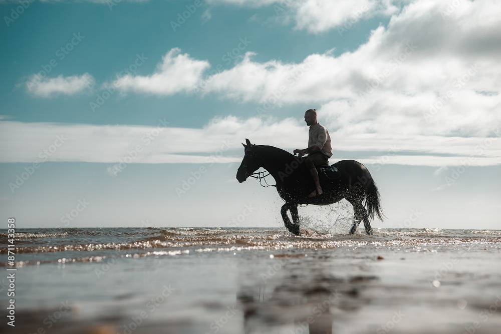 Fototapeta premium Man riding a horse on a beach, equestrian coastline scene, cowboy on horseback