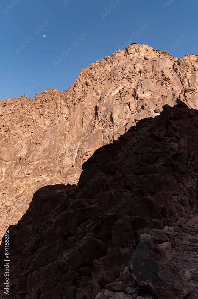 Rugged mountain terrain with moon in the sky Rugged mountain terrain with moon in the sky