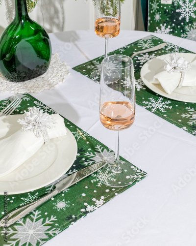 Festive holiday table setup with green snowflake-themed placemats and champagne flutes, perfect for a Christmas or winter celebration photo