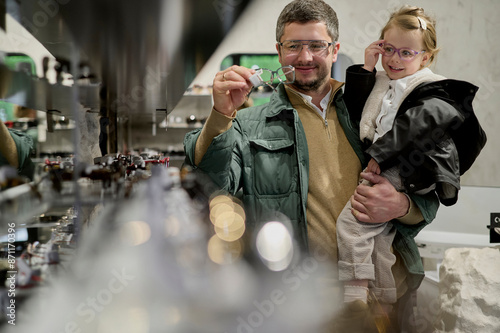 Dad choosing glasses with his littke daughter photo