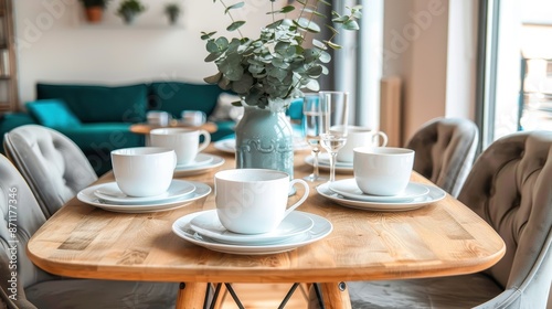 Wallpaper Mural A modern dining table set with white dishes and cups, centered with a eucalyptus arrangement, all placed in a light-filled room with a cozy ambiance. Torontodigital.ca