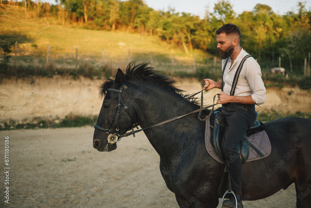 Side view of a handsome cowboy riding a horse at rural ranch. Side view of a handsome cowboy riding a horse at rural ranch.