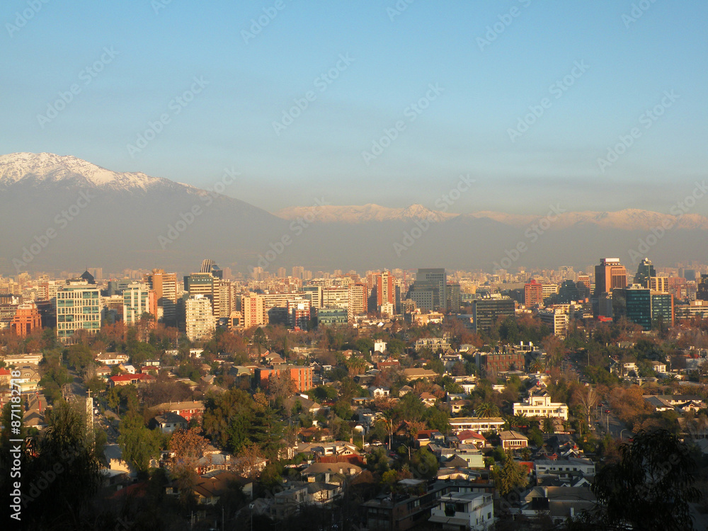 Obraz premium Buildings in Providencia at sunset with snowy mountain range in the background and air pollution