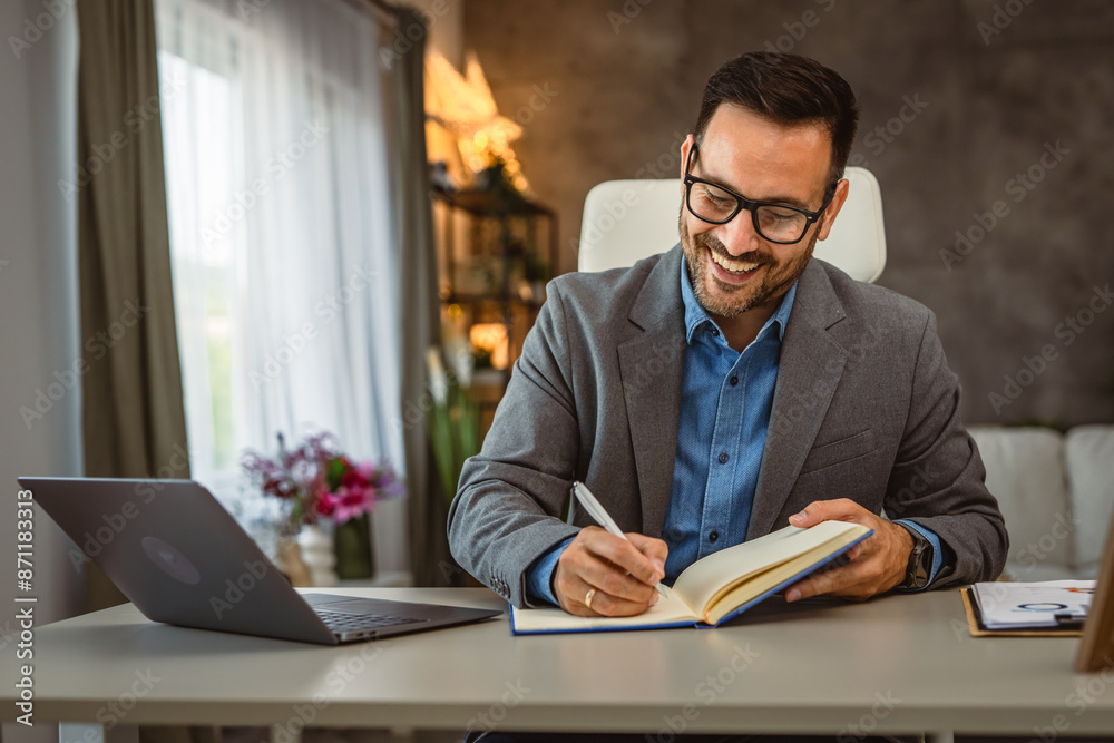 Adult man work from home write data from the laptop in a notebook