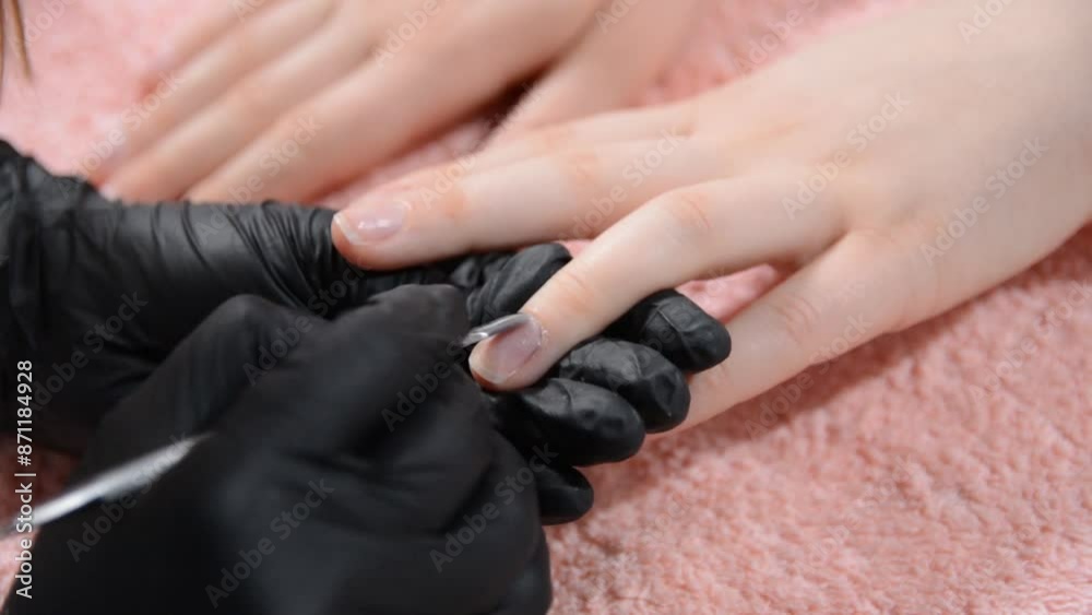Close-up of a beautician using a specialized tool to remove cuticles on a clients hand in a beauty salon, concept of manicure Close-up of a beautician using a specialized tool to remove cuticles on a clients hand in a beauty salon, concept of manicure