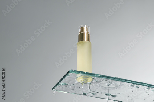 Yellow skin care essence, transparent bottle, liquid flowing off photo