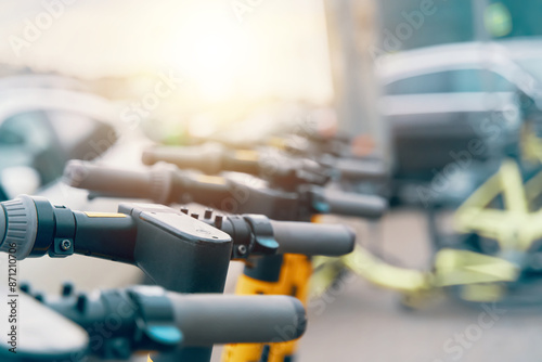A line of electric scooters is parked in a lot, showcasing the latest in engineering and technology for ecofriendly transportation