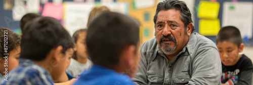 A middle-aged man with a beard is speaking to a group of students in a classroom setting