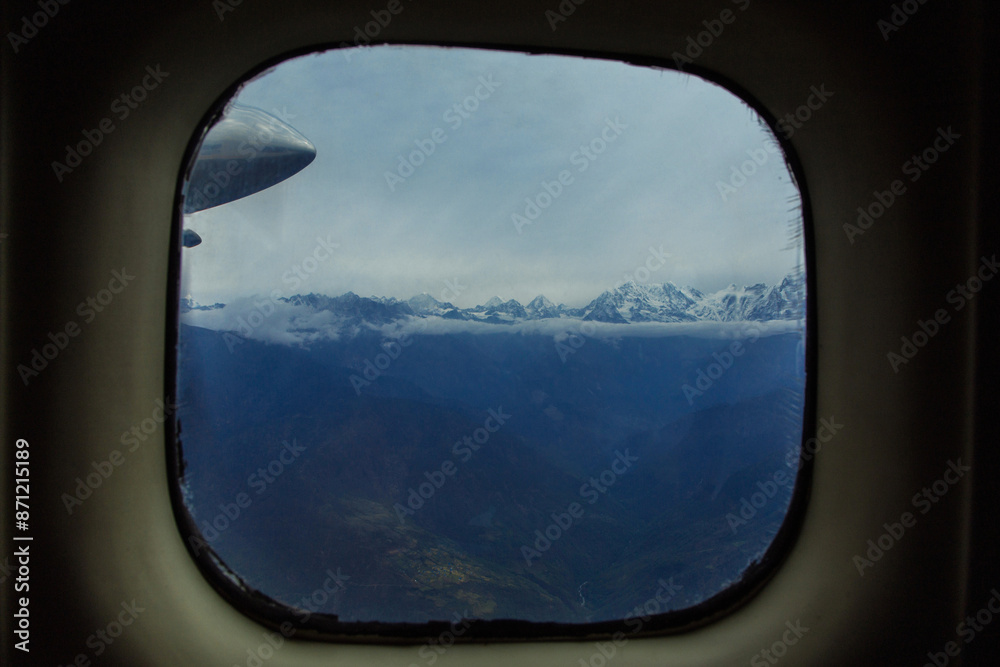 View of snow-capped mountains from an airplane window View of snow-capped mountains from an airplane window