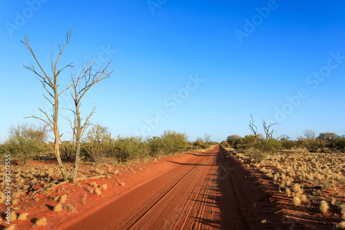 Remote red dirt road. Outback Australia. Blue sky with copy space.