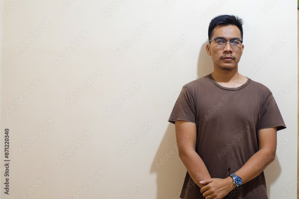 A Southeast Asian man with beard wearing brown t shirt background with hold arms looking at the camera, Seriously person. A Southeast Asian man with beard wearing brown t shirt background with hold arms looking at the camera, Seriously person.