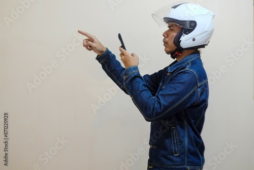 A Southeast Asian man wearing helmt and holding smartphone isolated over cream background, driver taxi online. stock photo. photo