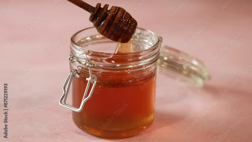 A close-up of a jar filled with golden honey, featuring a wooden honey dipper A close-up of a jar filled with golden honey, featuring a wooden honey dipper