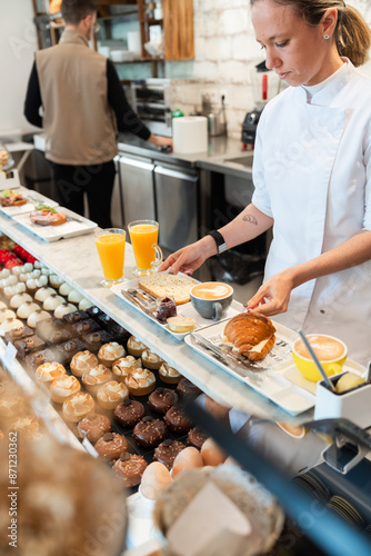 Pastry chef arranging freshly baked goods at cafe counter