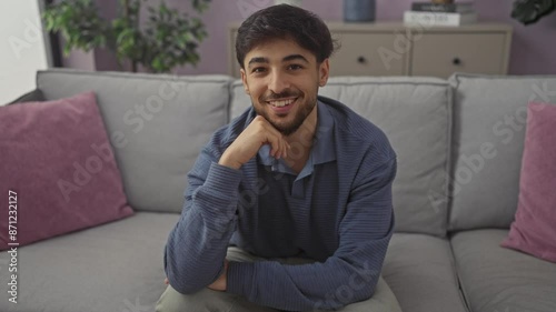 Arab man with beard smiling casually on couch at modern home photo