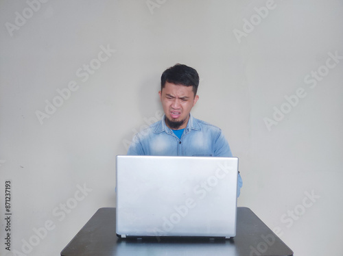 A man on his working place looking to laptop with shocked expression photo