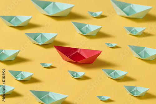 Leadership concept using red paper ship among with the white ones photo