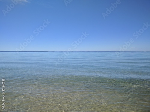 Photography placid lakeside scene with clear blue waters and the outline of grand traverse b