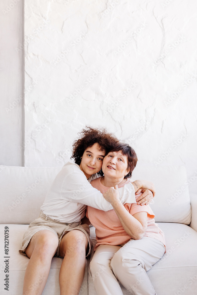 A girl and her grandmother are sitting on the couch cuddled together A girl and her grandmother are sitting on the couch cuddled together