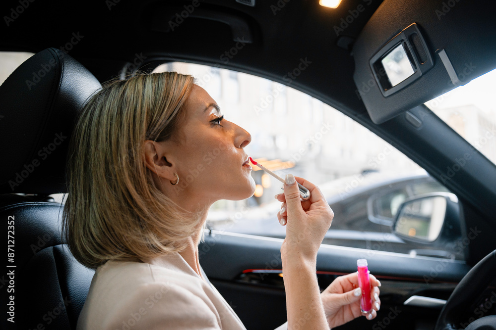 A woman paints her lips in a car A woman paints her lips in a car