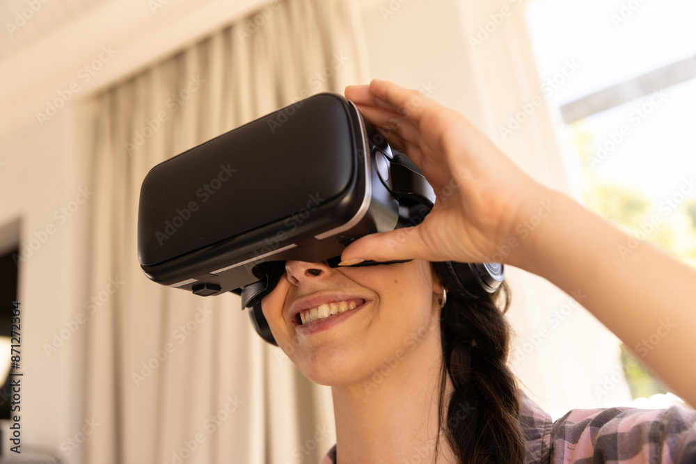 Using VR headset, woman smiling and enjoying virtual reality experience at home