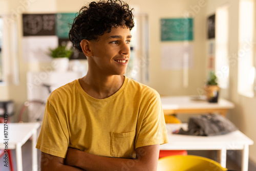 Smiling teenage boy in high school classroom, looking out window during break time