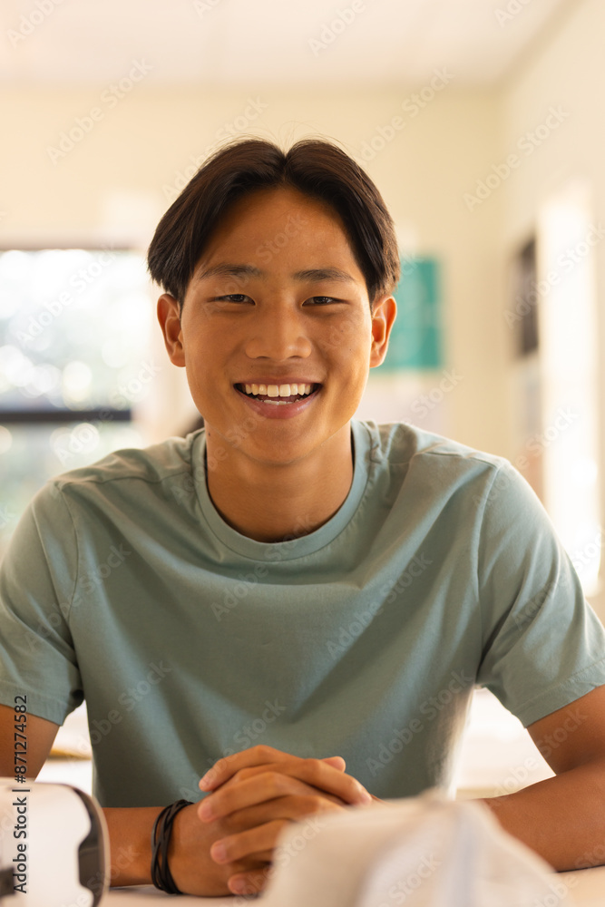 Smiling teenage boy sitting at high school desk, looking at camera in classroom Smiling teenage boy sitting at high school desk, looking at camera in classroom
