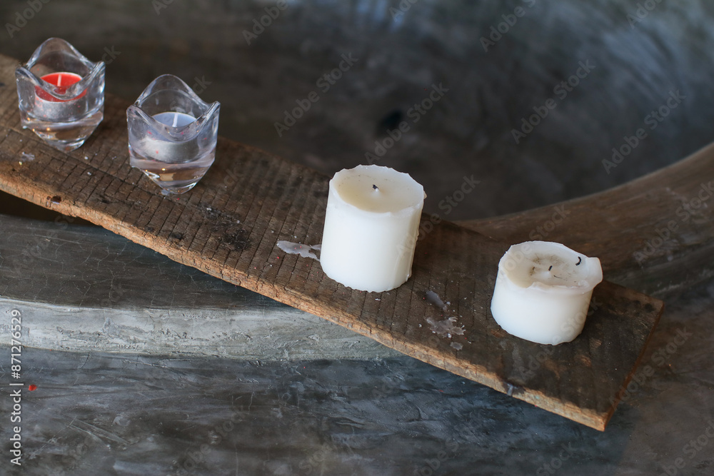 Burning white candle on wooden board. Home decoration. Handmade. Air freshener. Soy candle. Textured background creating an intimate atmosphere. concept Burning white candle on wooden board. Home decoration. Handmade. Air freshener. Soy candle. Textured background creating an intimate atmosphere. concept