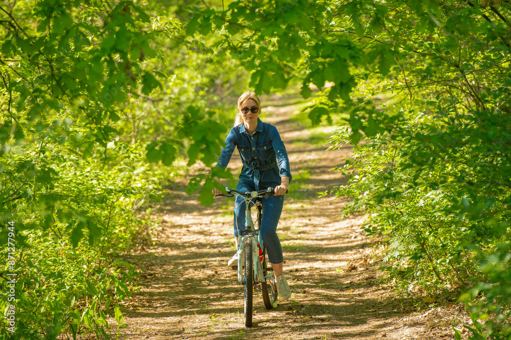 Fototapeta premium beautiful blonde rides a bike in the forest