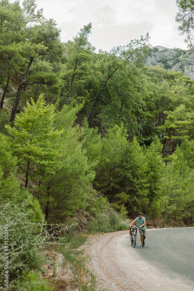 A man rolls a bicycle with a child in a child seat