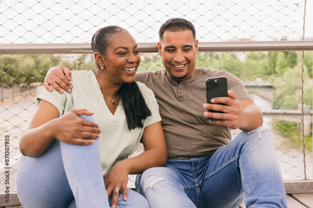 Curvy Dominican couple enjoying time on a bench with a smartphone Curvy Dominican couple enjoying time on a bench with a smartphone