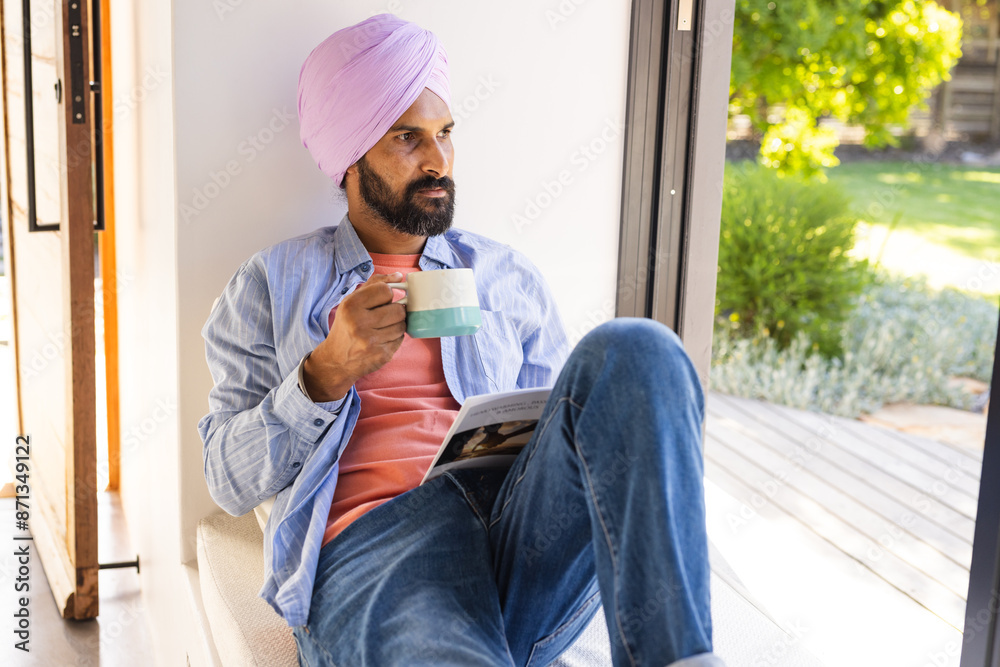 Relaxing at home, man with turban drinking coffee and reading book Relaxing at home, man with turban drinking coffee and reading book